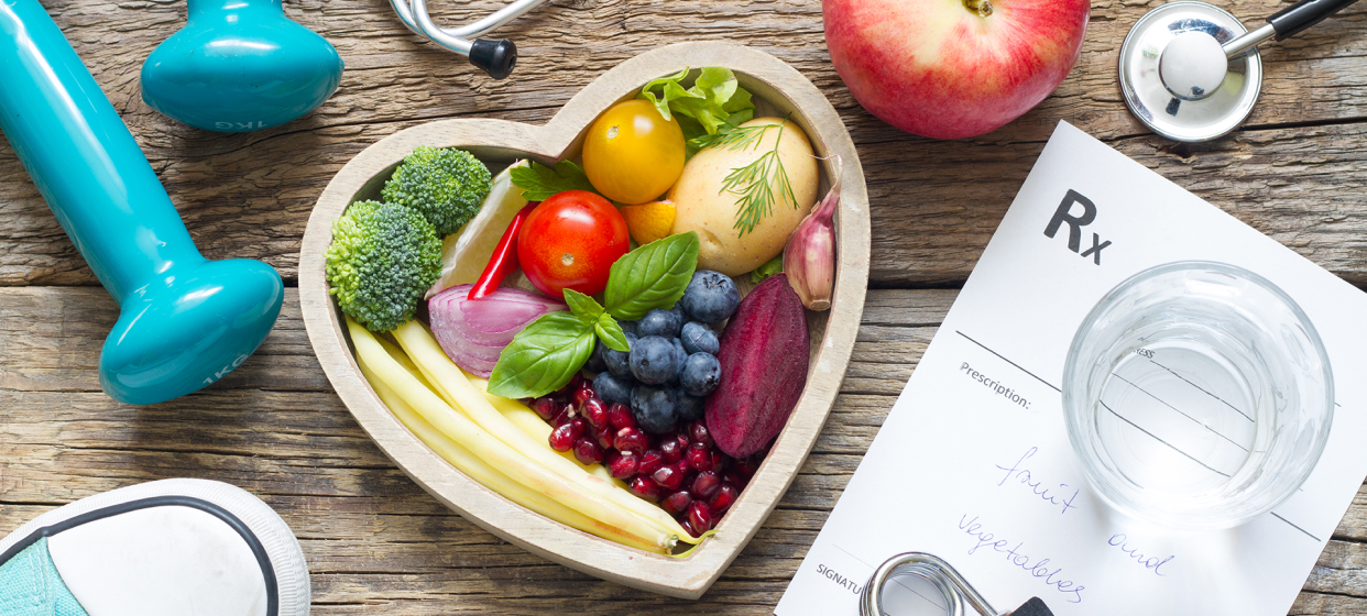 An image shows a heart-shaped bowl full of vegetables and fruits and a prescription on the table.