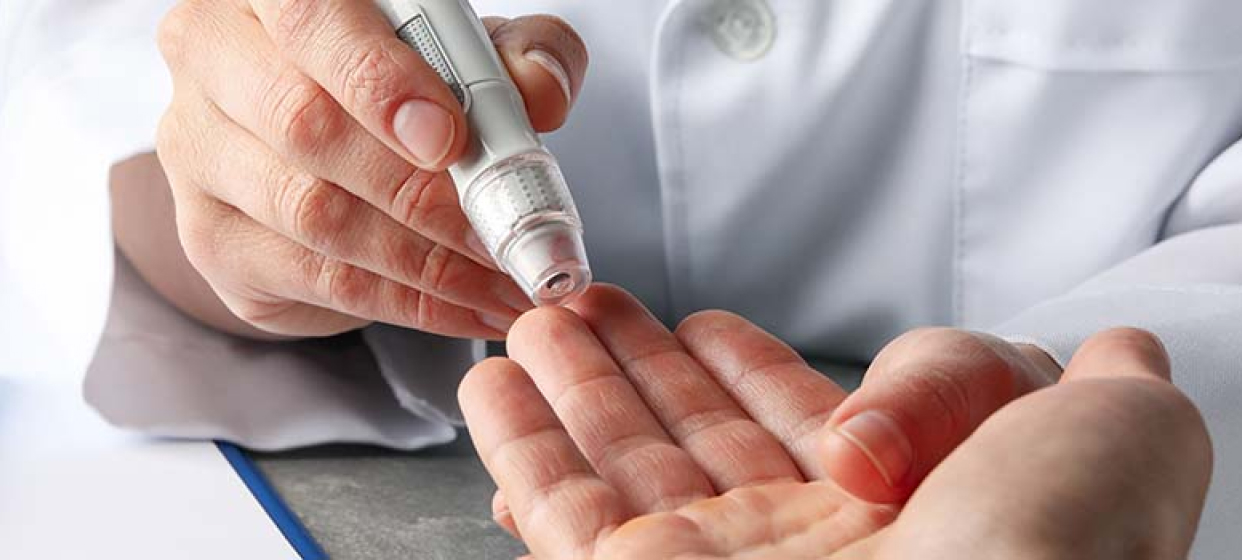 A picture of a doctor measuring his patient's diabetes with a monitoring device.