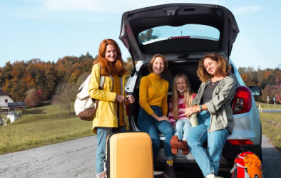 An image shows a group of women standing with a car trunk open, each holding a backpack.