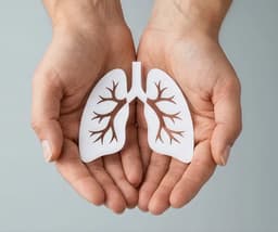 Hands holding a white paper cutout of lungs.
